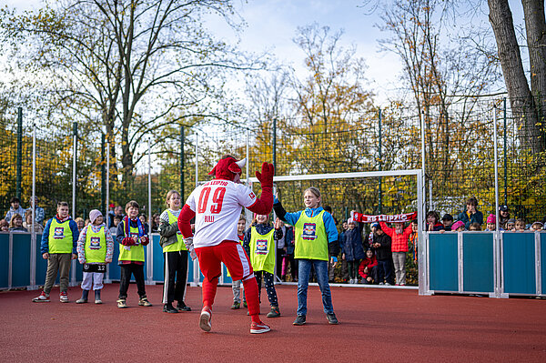 Schüler und Bulli ein Stiermaskottchen klatscht mit einem Schüler ein