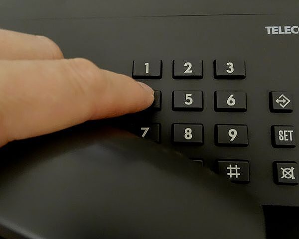 Person typing number into a telephone
