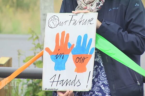 Hände halten ein bemaltes Plakat, darauf sind 2 Hände zu sehen und der Text "Our future in our hands"