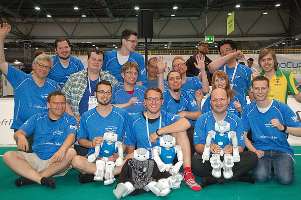 Das Nao-Team HTWK steht gemeinsam auf einem Spielfeld bei dem RoboCup 2016