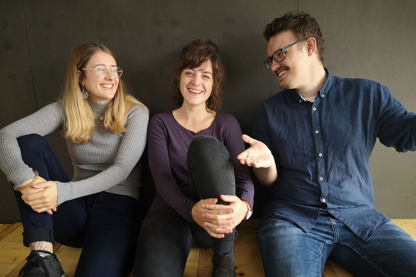 Three smiling students sitting next to each other