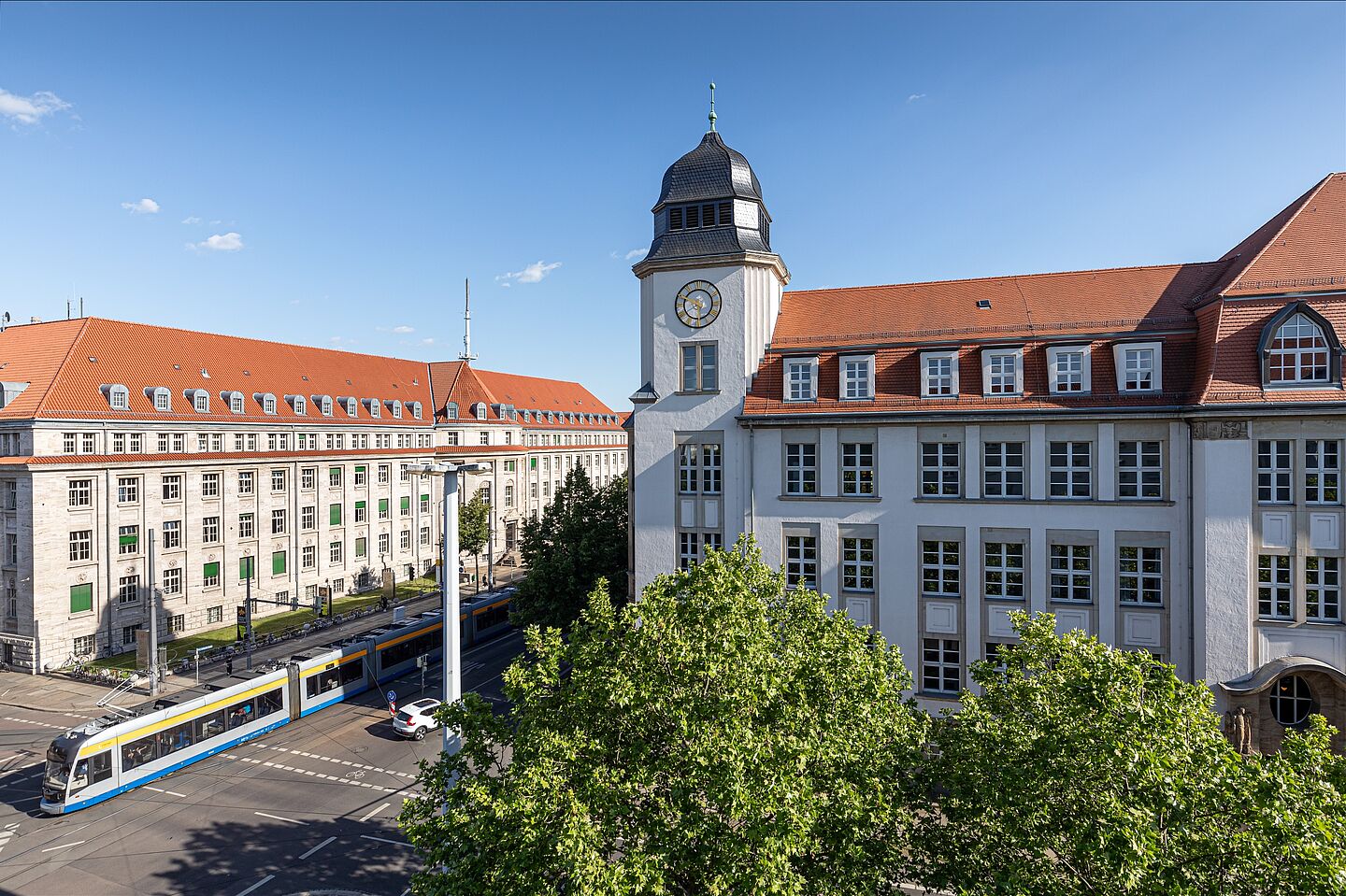 Blick auf eine Straßenkreuzung mit einer Straßenbahn und angrenzenden HTWK-Gebäuden.