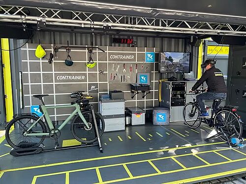 Innenraum des sogenannten "Contrainers" - eines Containers mit einem Werkstattbereich links und einem fest installierten Fahrrad rechts, auf dem man eine VR-Anwendung spielen kann