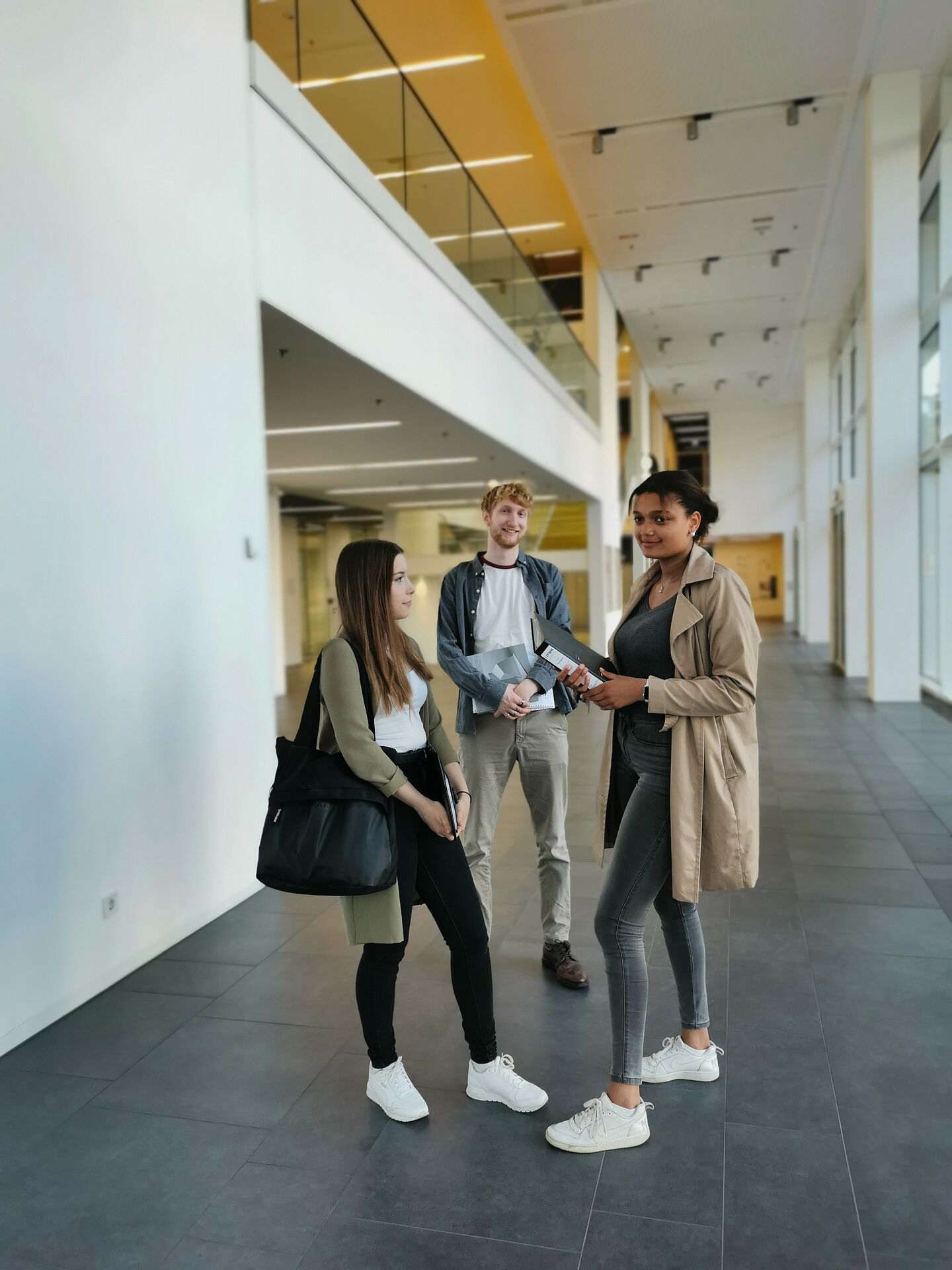 drei Personen in einem modernen Foyer