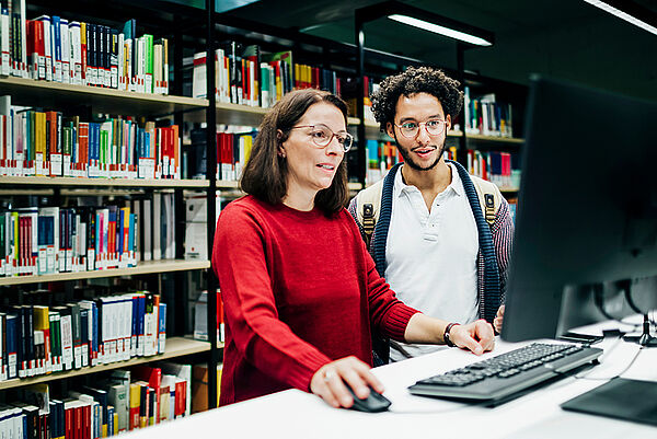 eine Frau erklärt einem Studenten etwas am Computer