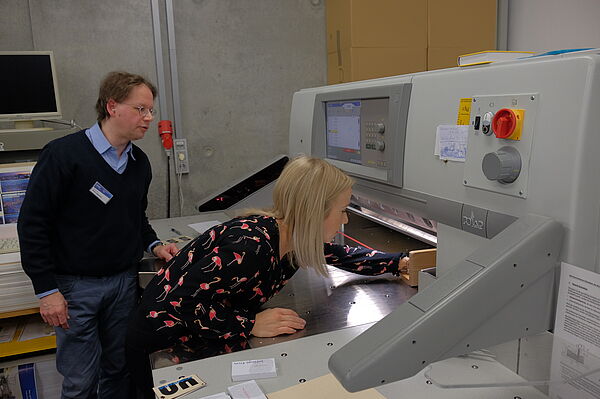 Ein Laboringenieur mit einer Interessentin an einer Druckmaschine im Labor.