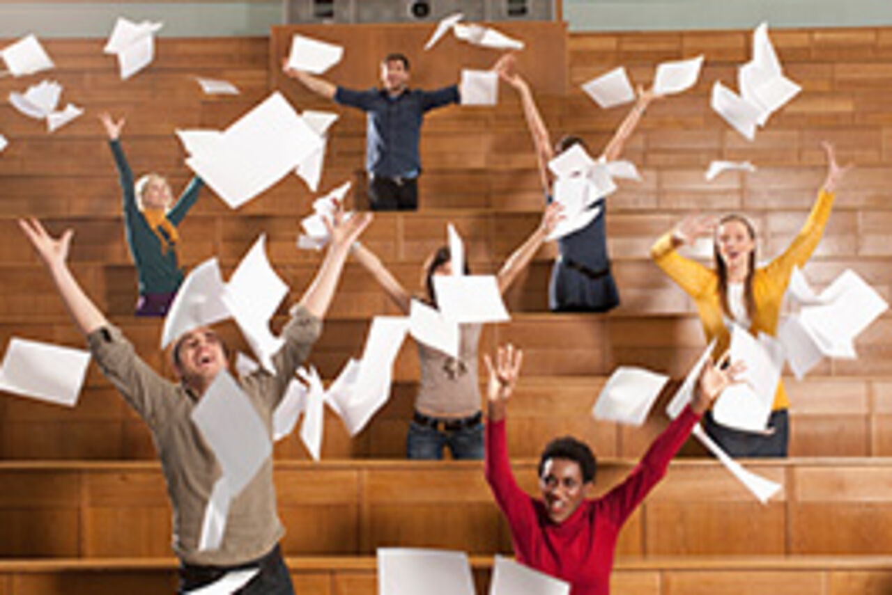 Students celebrate in a lecture hall and let their papers fly