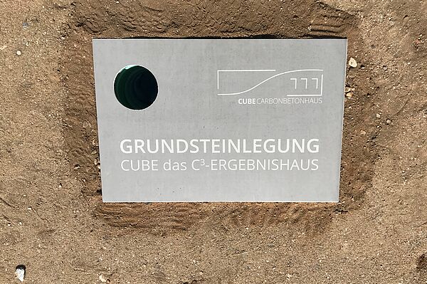 Rechteckiger Grundstein mit einem Loch zum Einlassen der Zeitkapsel. Auf dem Grundstein steht: Grundsteinlegung. CUBE das C3-Ereignishaus.