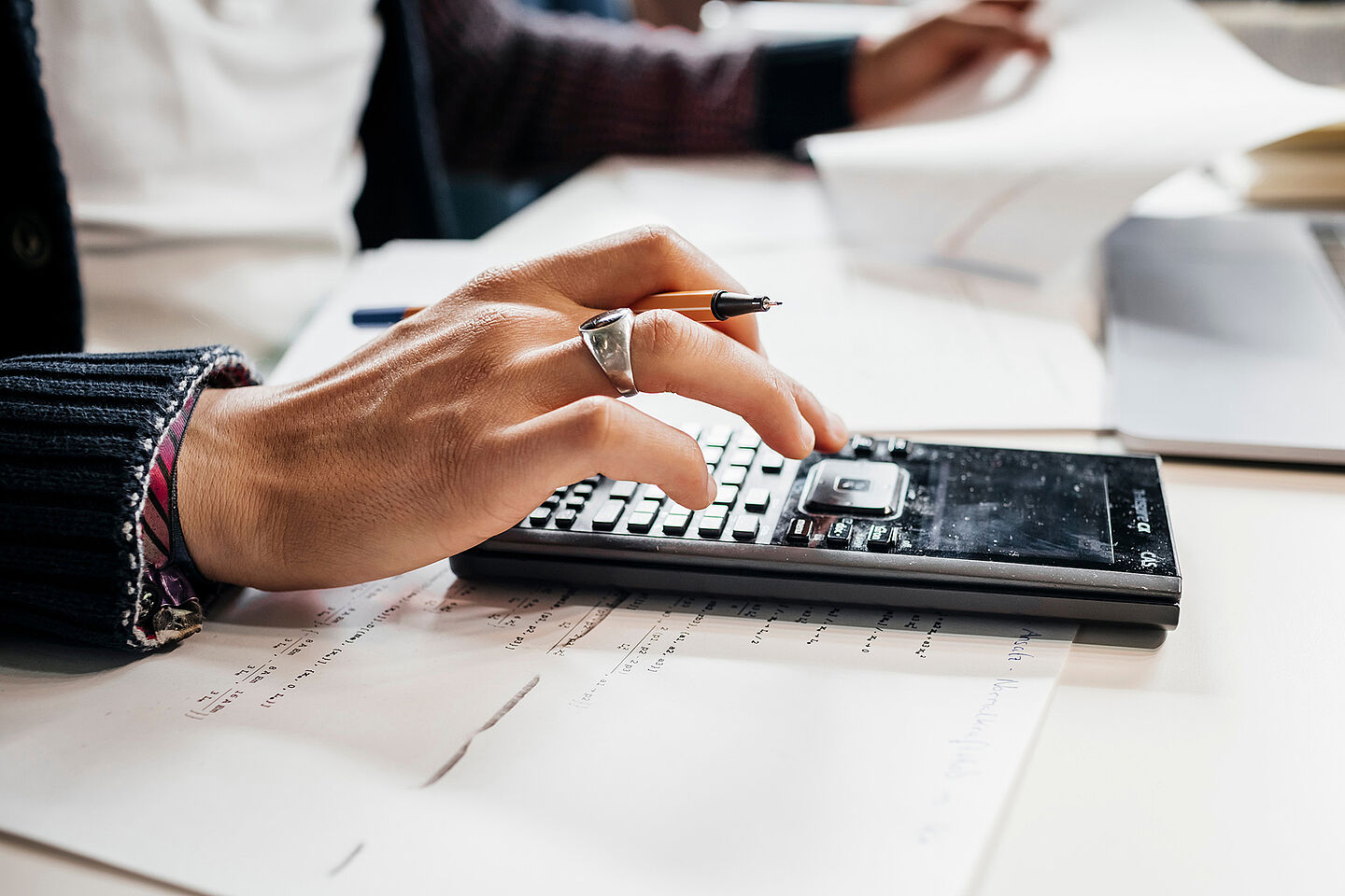 A person calculates with a pocket calculator