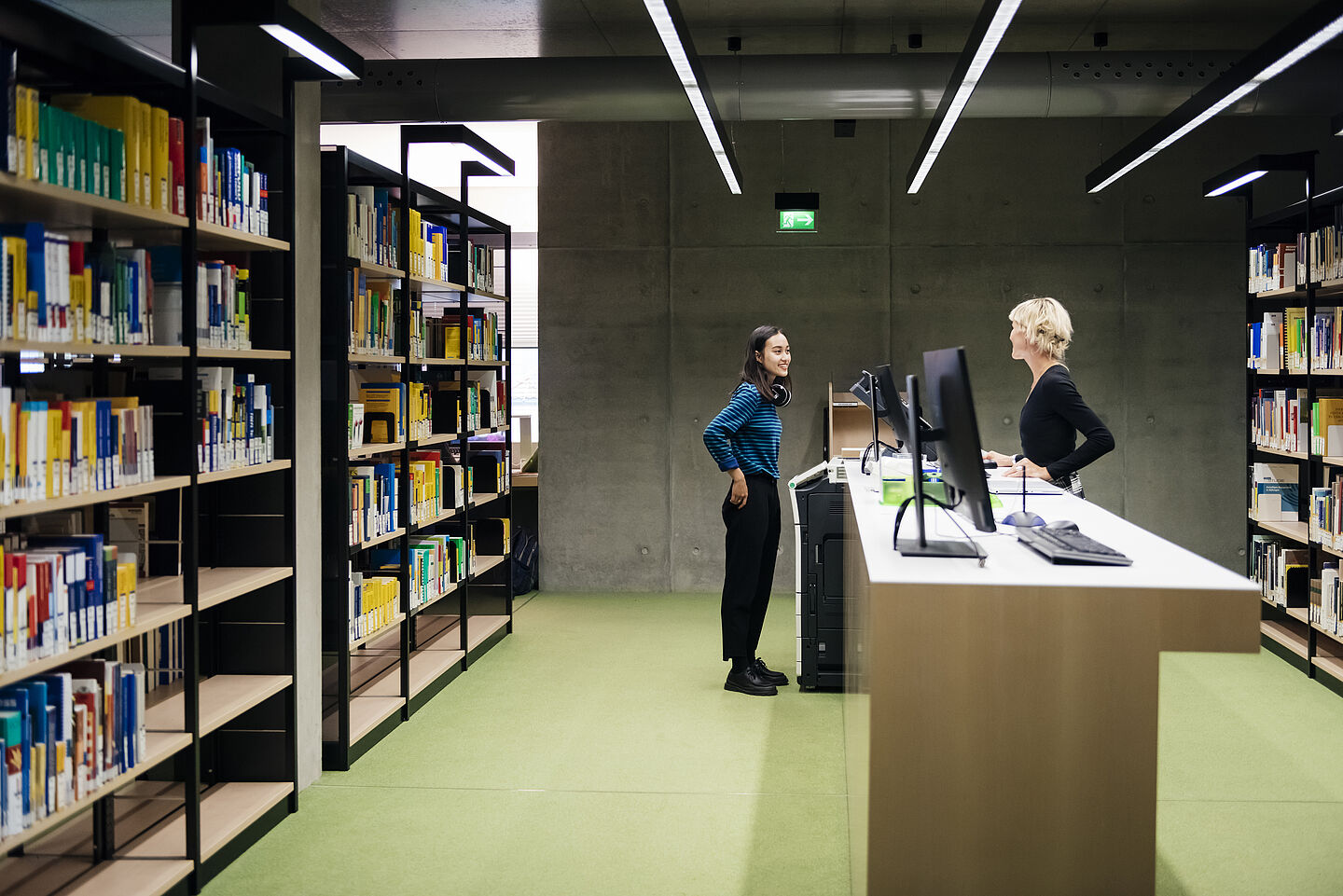 Zwei Studentinnen stehen an einem Tresen der Hochschulbibliothek der HTWK.