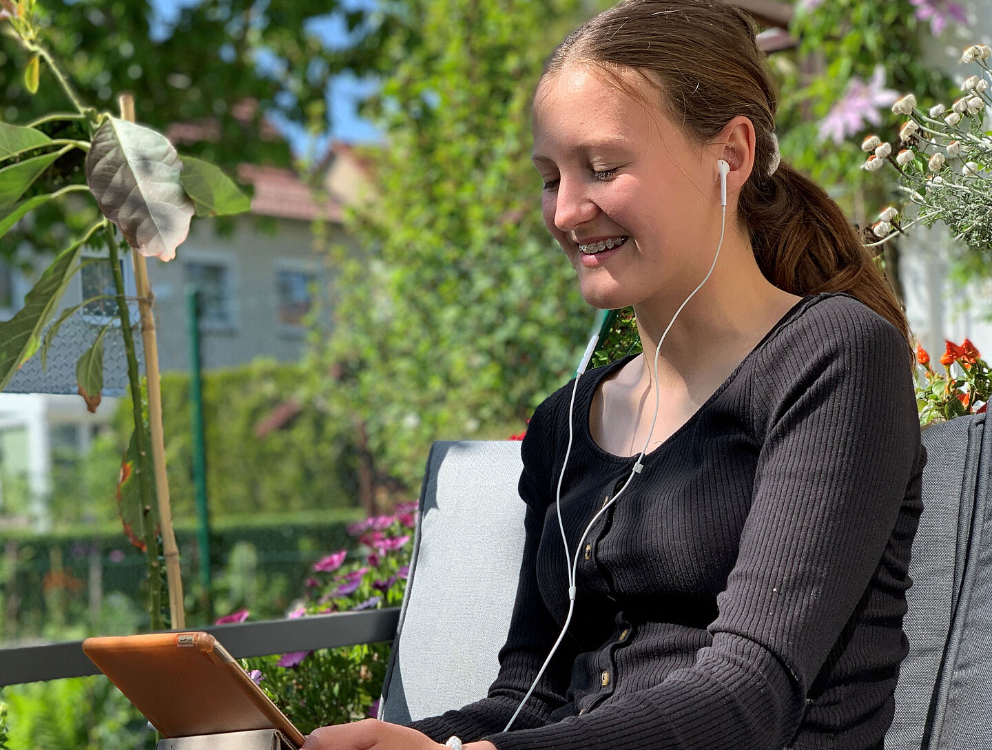 Eine junge Frau schaut auf ihr Tablet und hört über Kopfhörer etwas an