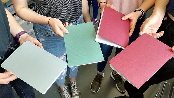 Hände zeigen vier selbstgemachte Hefte aus Papier