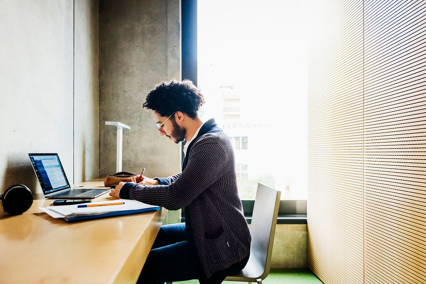 Person sits at desk with laptop and documents