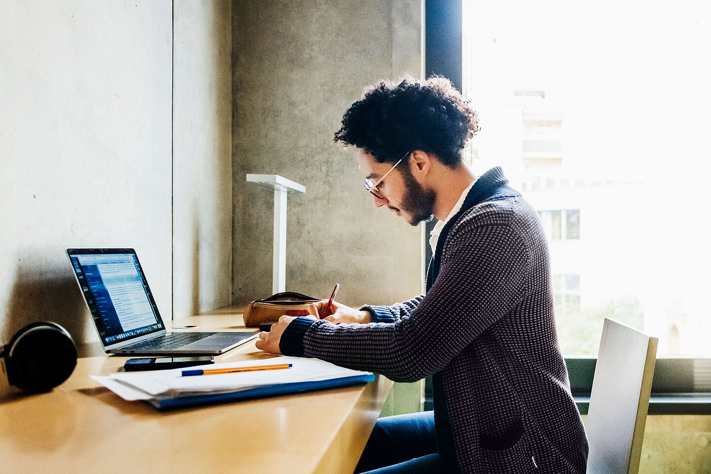 Person sits at desk with laptop and documents