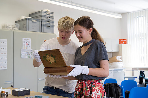 zwei Personen schauen sich ein Ogjekt an