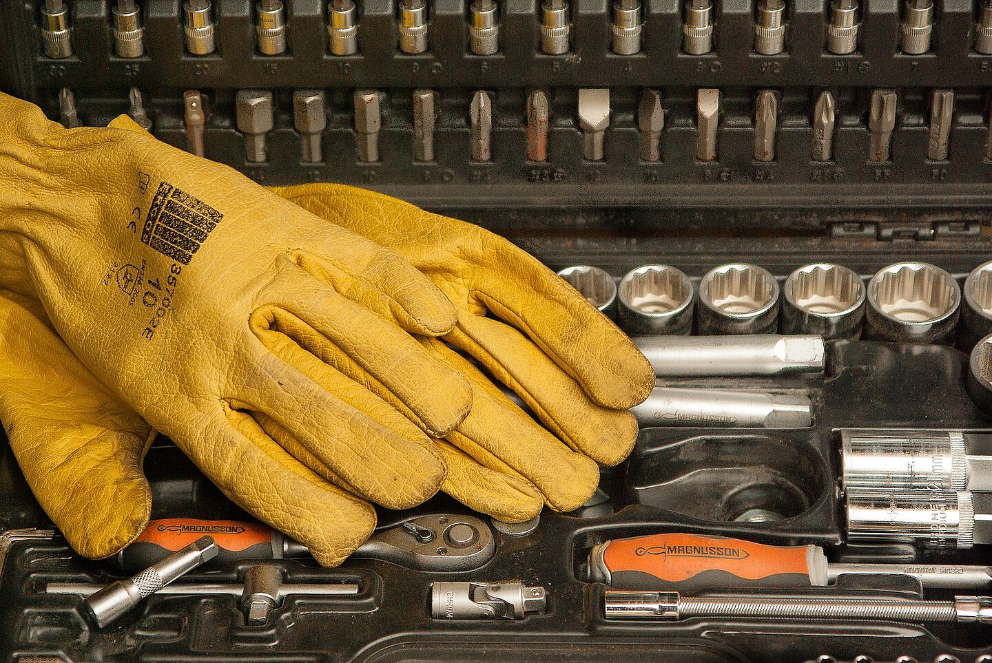 dreckige gelbe Arbeitshandschuhe und ein Werkzeugkasten