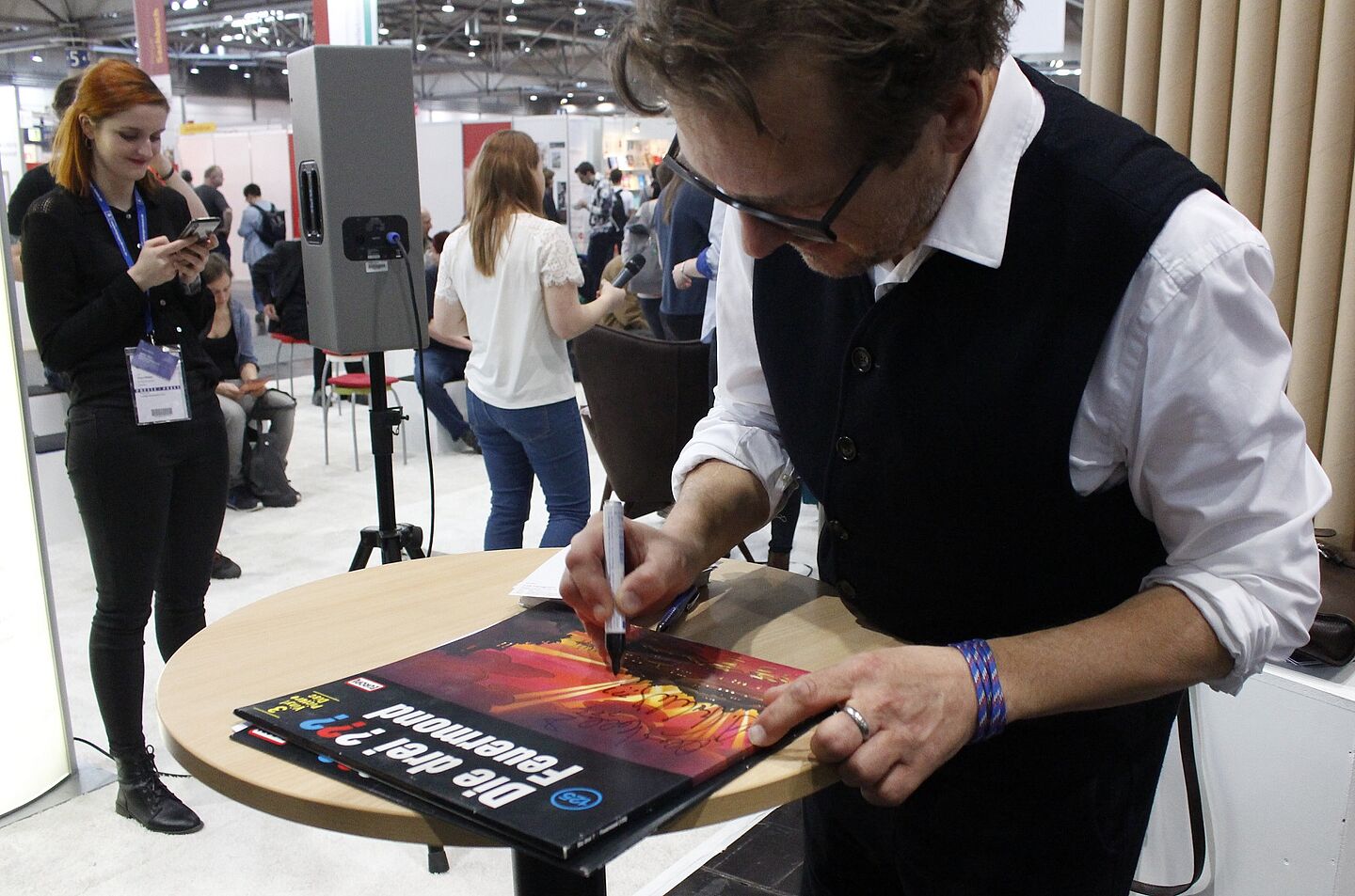 ein Mann am Messestand unterschreibt auf einer Schallplatte