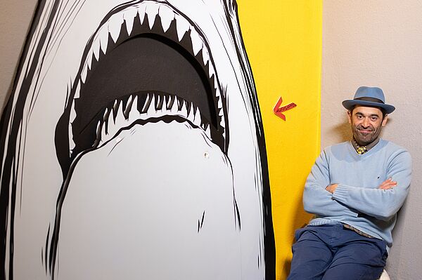 Mann mit Hut vor Grafik mit Hai