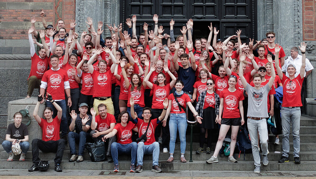 Gruppenbild der Teilnehmenden der HTWK-Radtour in roten Shirts und jubelnd