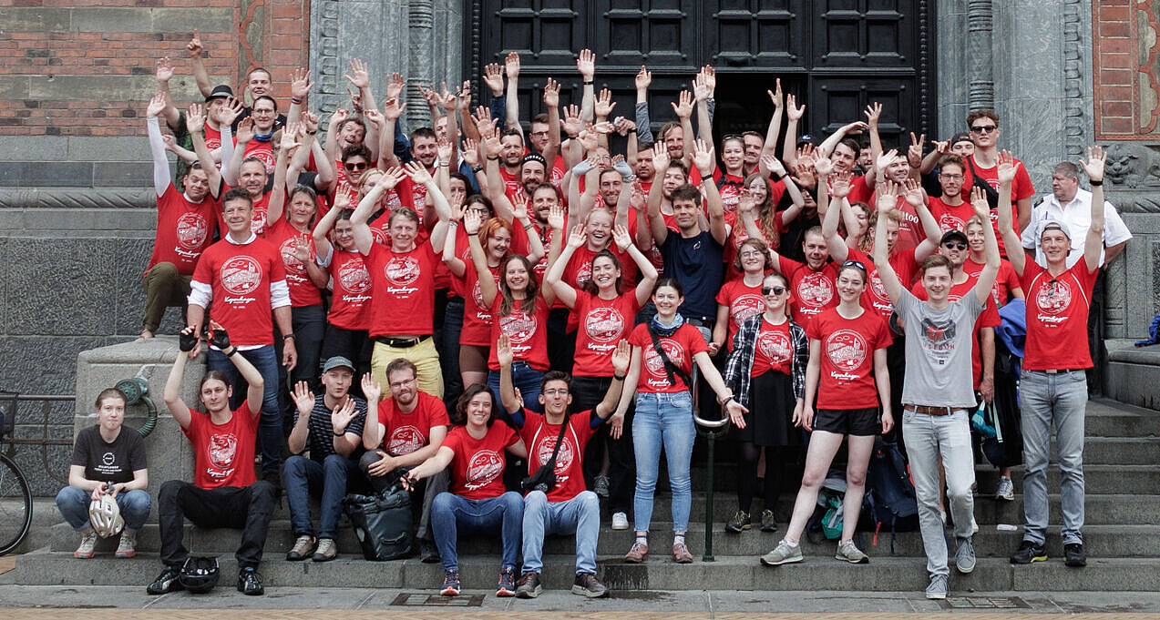 Gruppenbild der Teilnehmenden der HTWK-Radtour in roten Shirts und jubelnd