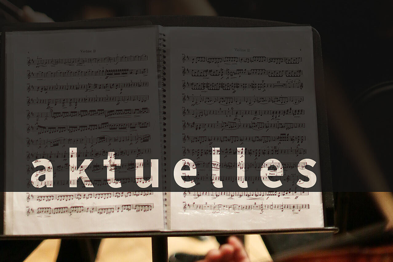 Über das Bild eines aufgeschlagenen Notenhefts wurde per Computer das Wort "aktuelles" gelegt.