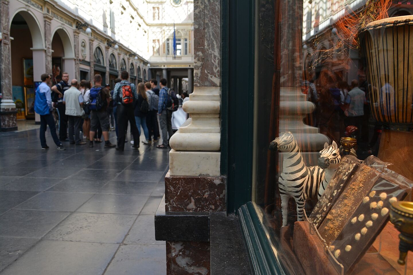 Innenblick in eine edle Passage. In der Mall steht eine Gruppe, in einem Schaufenster ist Schokolade zum Kauf ausgestellt.