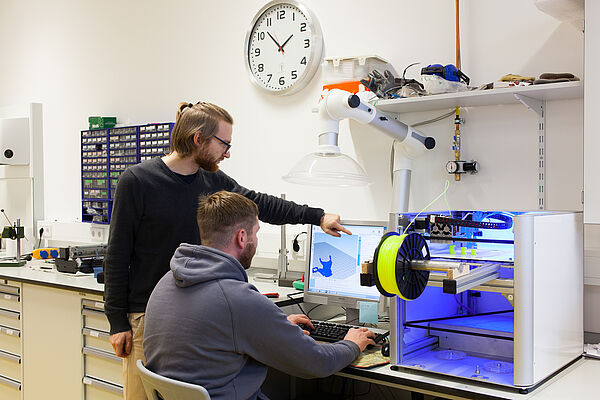 Zwei Studenten vor einem 3D-Drucker.