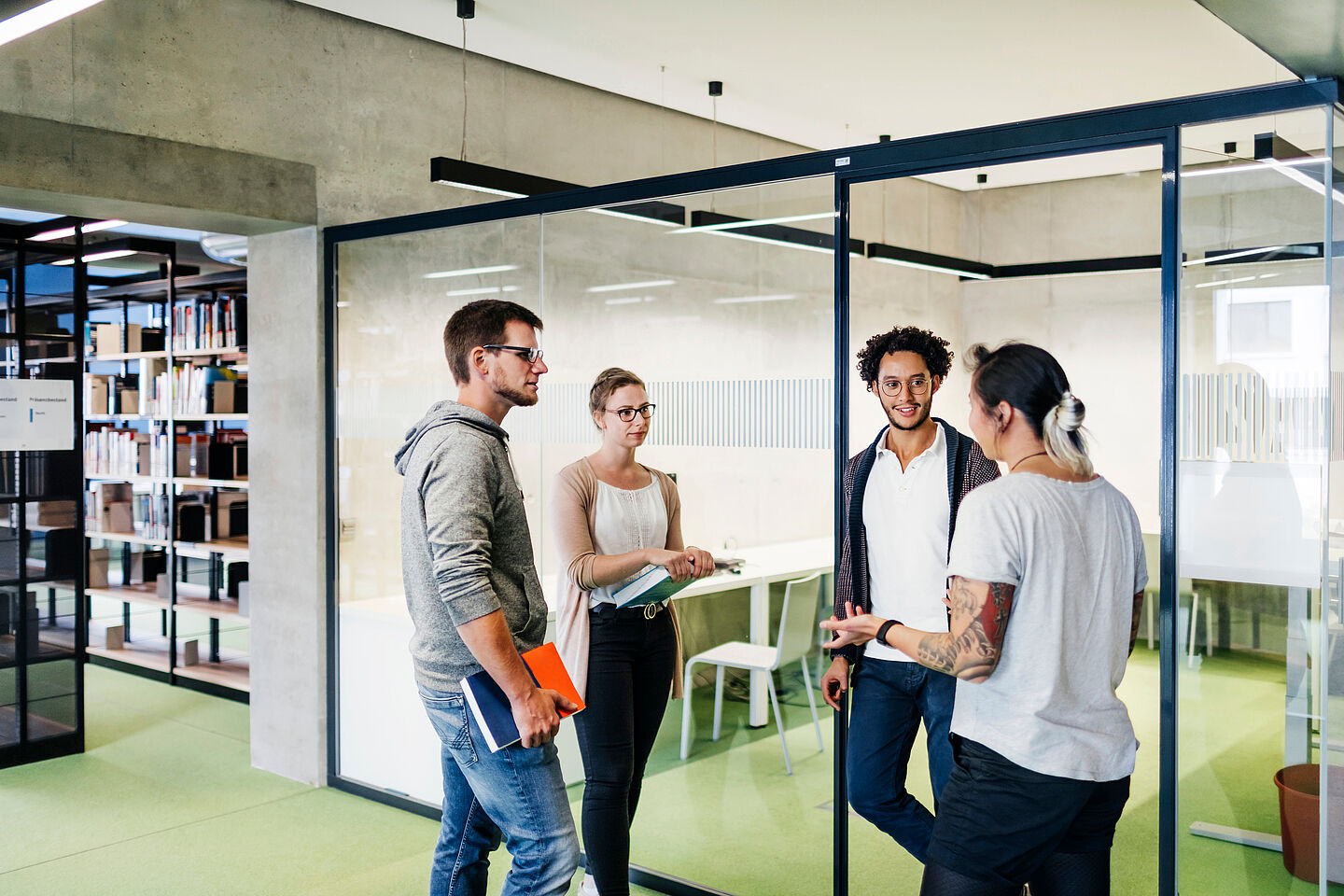 Four students stand in the library talking