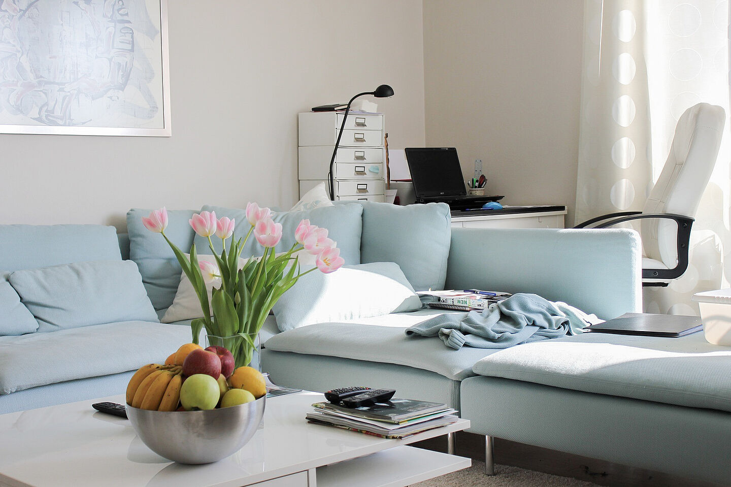 Bright living room with coffee table, blue sofa and work area