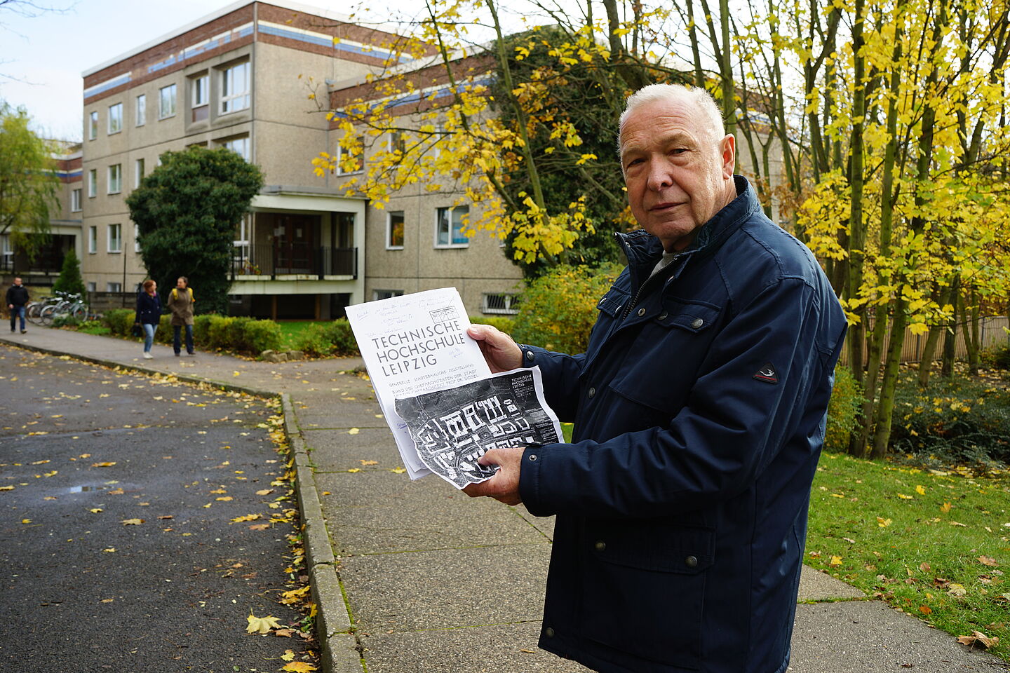 Zeitzeuge Dr. Jochen Staude steht vor dem heutigen Kindergarten in der Richard-Lehmann-Straße. In der Hand hält er Planungsunterlagen, die das Gelände als Hochschul-Areal vorsahen.