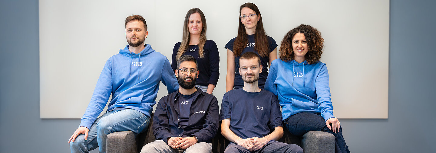Teamfoto Startbahn 13 6 Personen sitzen auf einer Couch