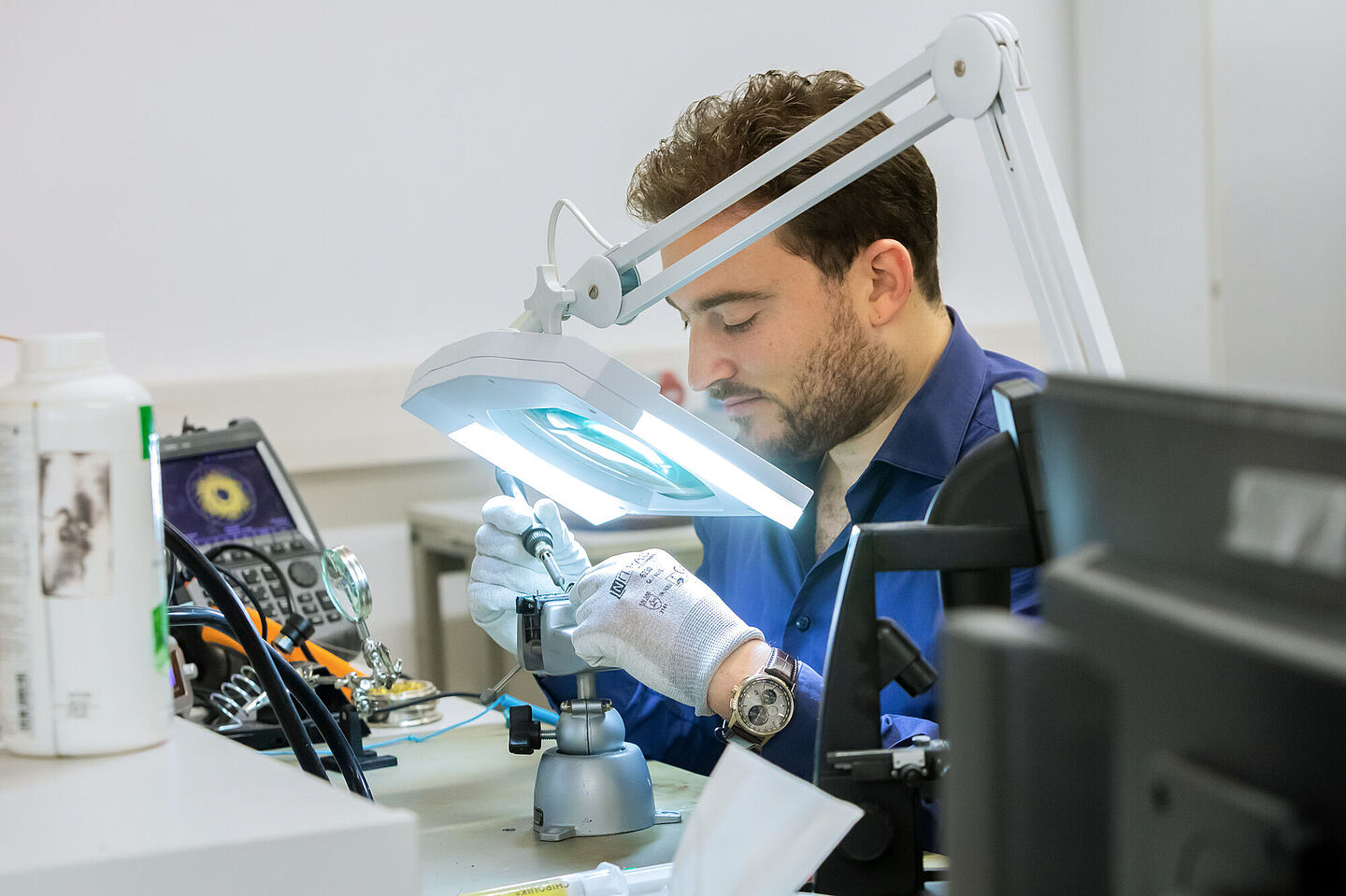 Person at the work table soldering a small component