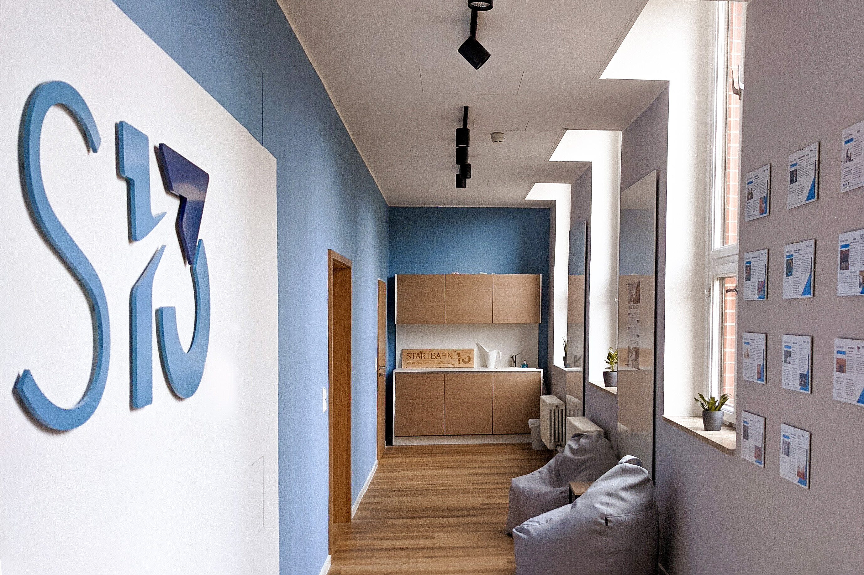 Gründungsberatung Startbahn 13 Ansicht des modernen Flur der Gründungsberatung mit einem großen Logo an der Wand, Sitzsäcken und einer kleinen Küchenzeile.