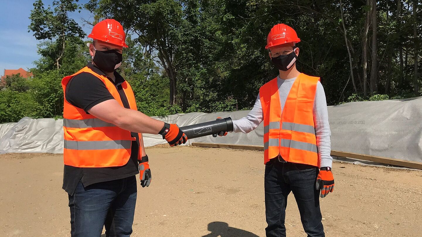 Matthias Tietze und Michael Frenzel bei der Grundsteinlegung. Beide berühren symbolisch die Zeitkapsel aus Carbon.