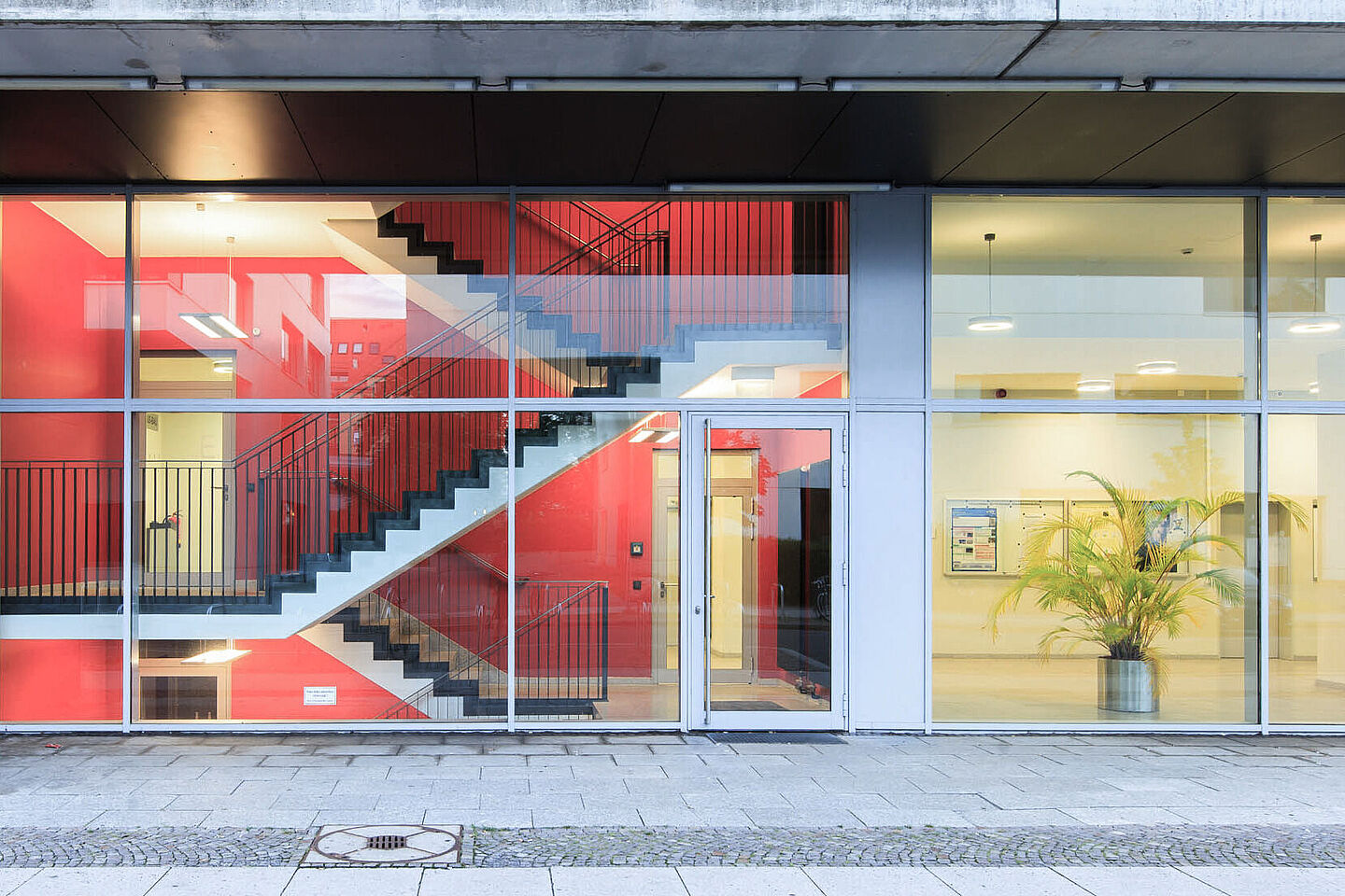 View of a glass façade, behind which a foyer and staircase can be seen