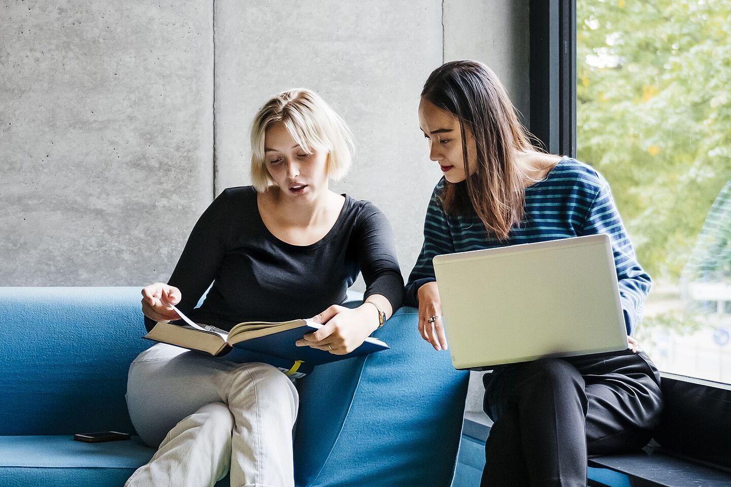 Two people on the couch looking into a book together