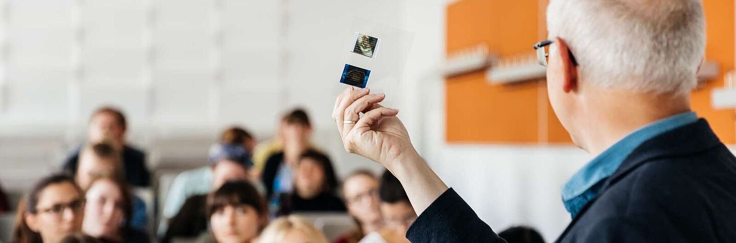 Lehrperson vor Hörsaalplenum