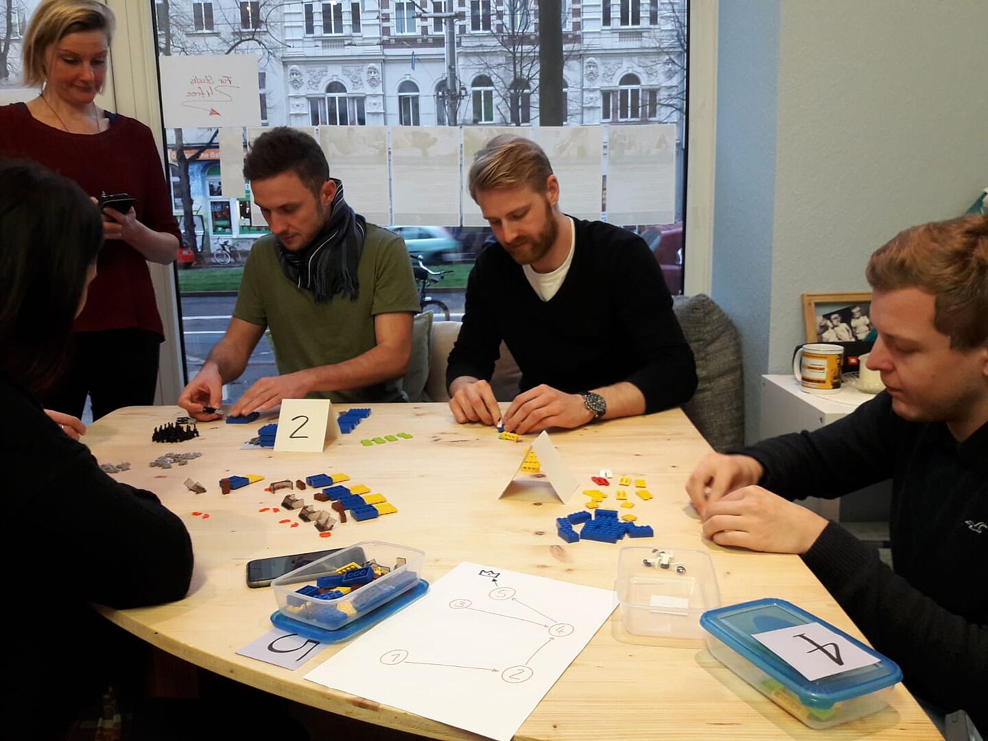 Eine Gruppe von Studierenden sitzt an einem Tisch und baut Lego zusammen.