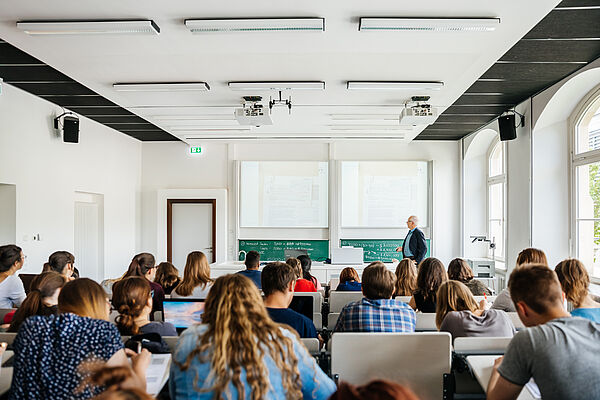 Studierende sitzen im Hörsaal und folgen einer Vorlesung