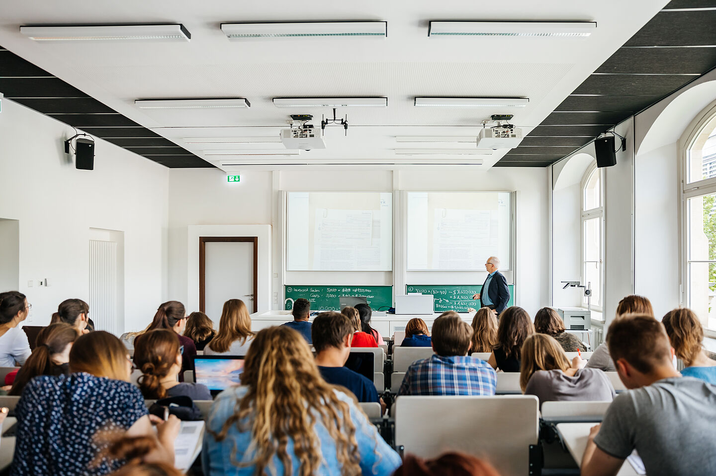 Studierende sitzen im Hörsaal und folgen einer Vorlesung