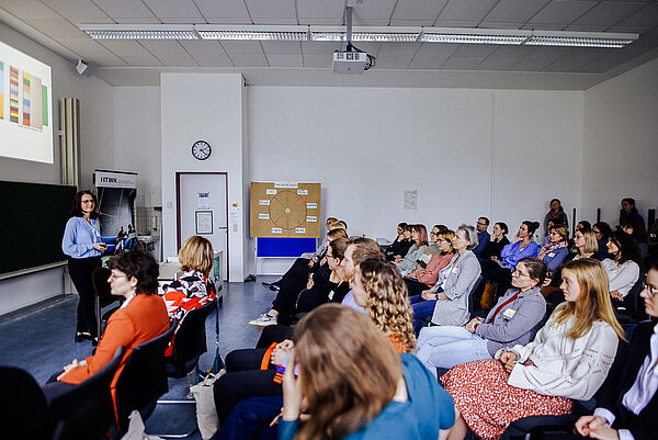 Keynote von Professorin Graßmann Professorin Graßmann steht vor dem Publikum und hält eine Keynote. Im Hintergrund auf der Wand ist ihre Powerpoint-Präsentation zu sehen.