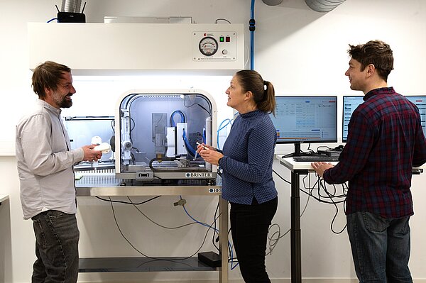 3D-Drucker Drei Personen stehen am 3D-Drucker