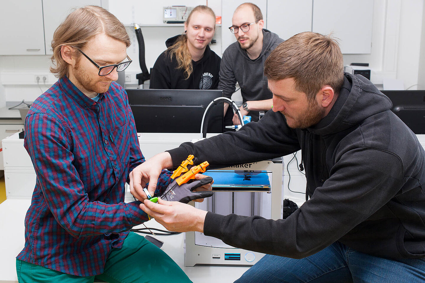 Four people researching an exoskeleton hand