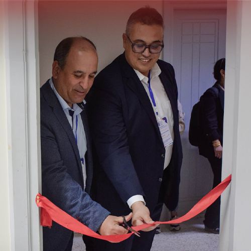 Professoren durchschneiden gemeinsam symbolisch ein rotes Band zwischen einer Tür