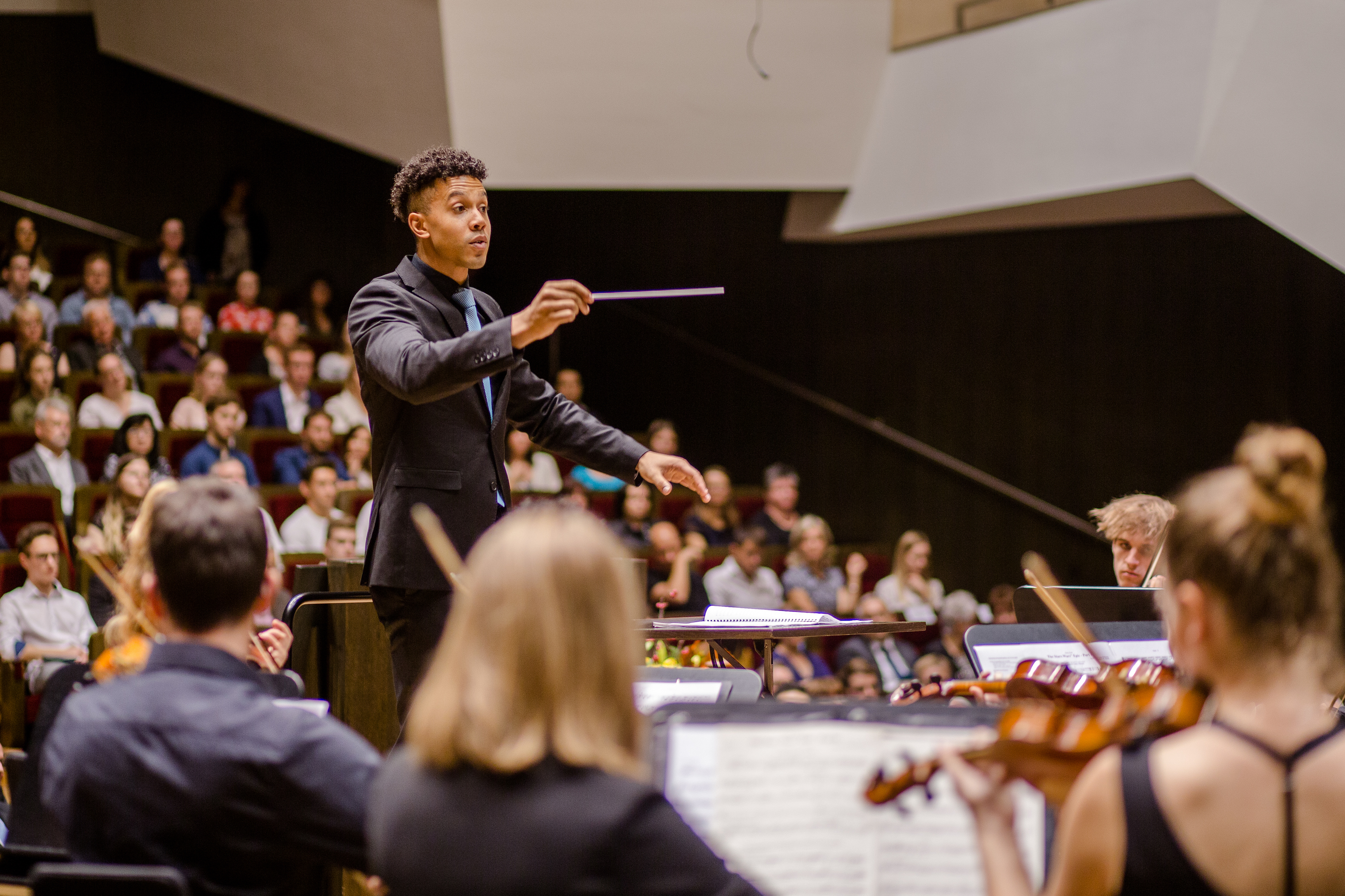 Während der feierlichen Immatrikulation spielt das HTWK Orchester im Gewandhaus. Man sieht meherer Menschen von hinten ihr Intrument spielen, vor ihnen steht der Dirigent.