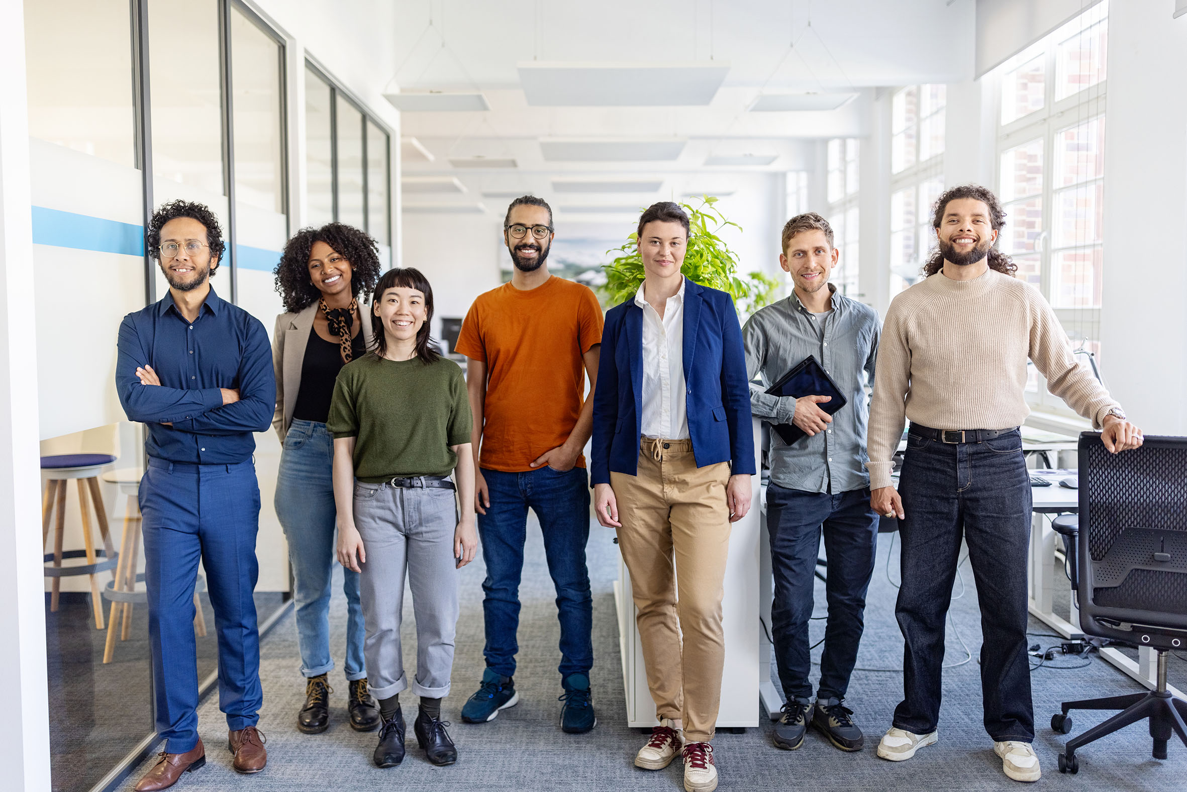 International Career Office Eine multikulturelle Gruppe von jungen Erwachsenen steht in einem Büro und alle schauen frontal in die Kamera.