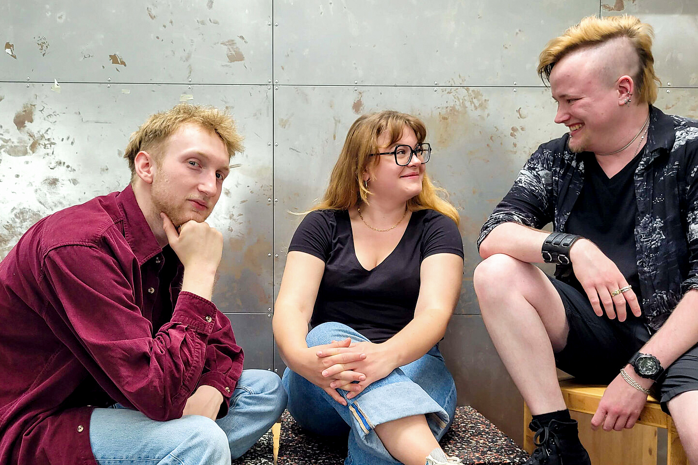 HTWK Insider Drei Studierende sitzen entspannt und fröhlich vor einer Wand.