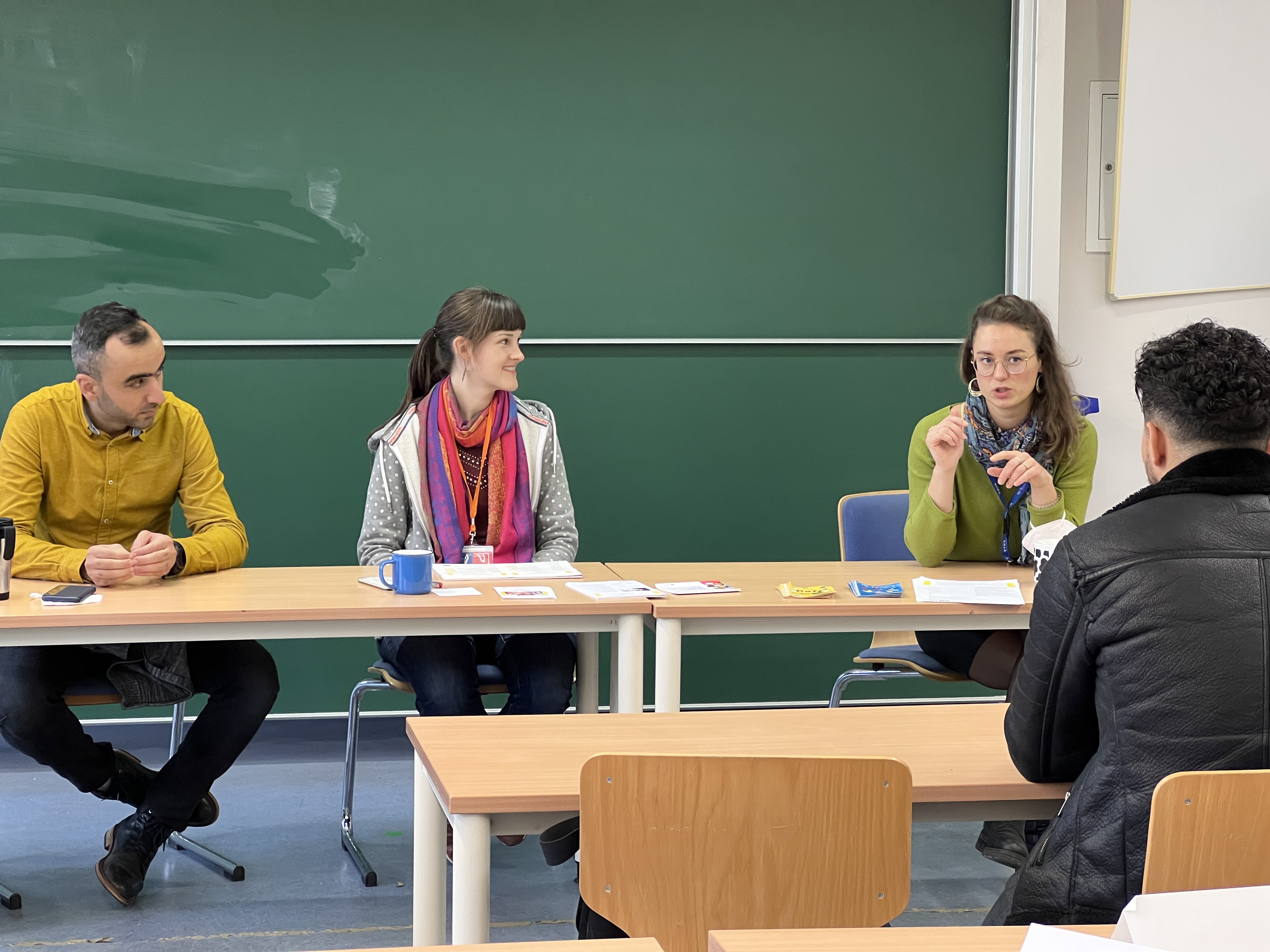 drei Personen an einem Tisch beraten vierte Person